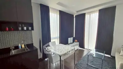 Modern living room with kitchenette, featuring sleek design and ample natural light from large windows.