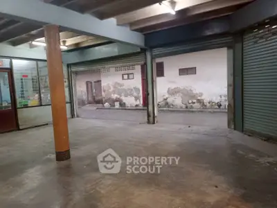 Spacious industrial-style garage with open shutters and concrete flooring, ideal for storage or workshop use.