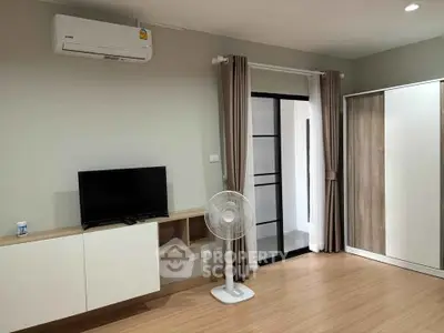 Modern living room with air conditioning, TV, and sliding glass door to balcony.