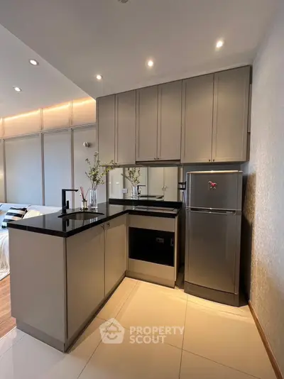 Modern kitchen with sleek cabinetry and stainless steel fridge in a stylish apartment.