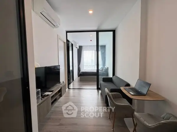 Modern apartment with open living room and bedroom, featuring sleek furniture and natural light.