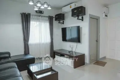 Modern living room with sleek furniture and wall-mounted TV, featuring stylish lighting and air conditioning.