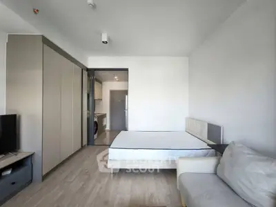 Modern studio apartment with minimalist design, featuring a cozy bed, sleek wardrobe, and compact kitchen area.