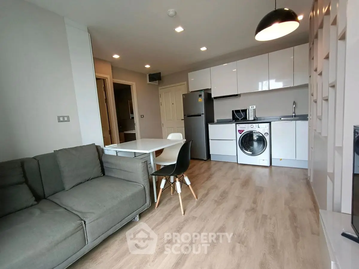 Modern open-plan living room with kitchen, featuring sleek appliances and stylish furniture.