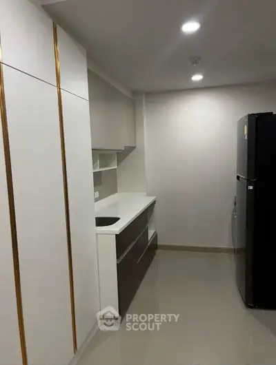 Modern kitchen with sleek cabinetry and stainless steel fridge in a minimalist design.