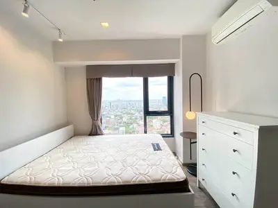 Modern bedroom with large window offering stunning city view, featuring minimalist decor and ample natural light.