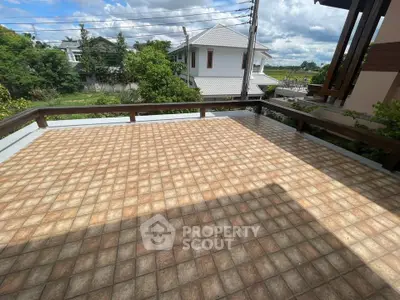 Spacious tiled balcony with scenic view of lush greenery and modern houses, perfect for outdoor relaxation.