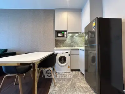 Modern kitchen with washing machine, fridge, and dining area in stylish apartment.