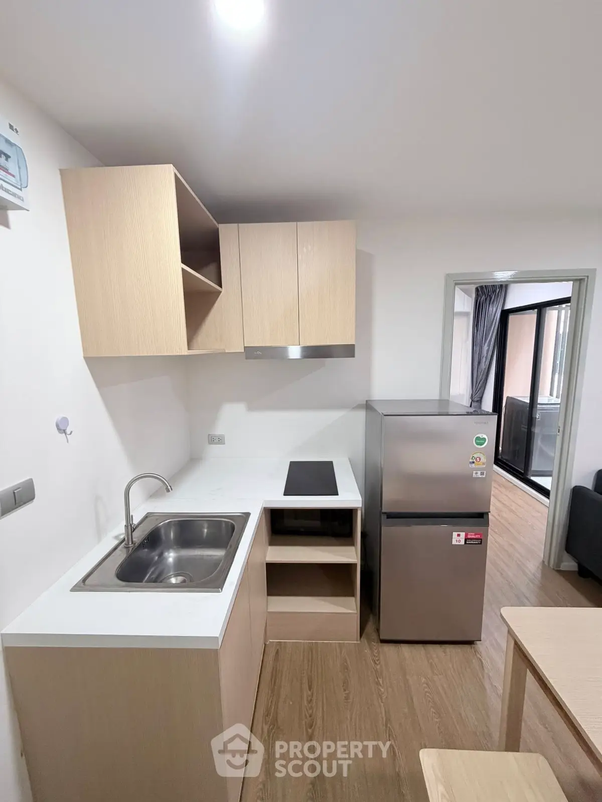 Modern compact kitchen with sleek cabinetry and stainless steel appliances in a cozy apartment.