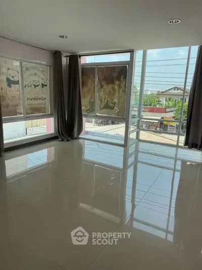 Spacious room with large windows offering ample natural light and city views, perfect for modern living.