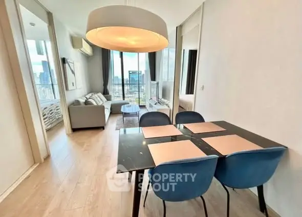 Modern open-plan living and dining area with city view, featuring stylish furniture and elegant lighting.