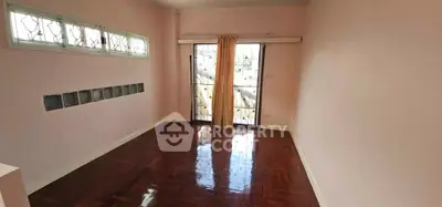 Spacious empty room with polished wooden floors and large window for natural light.
