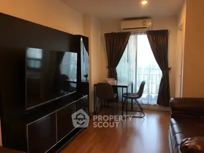 Modern living room with sleek furniture and large TV, featuring a cozy workspace by the window.