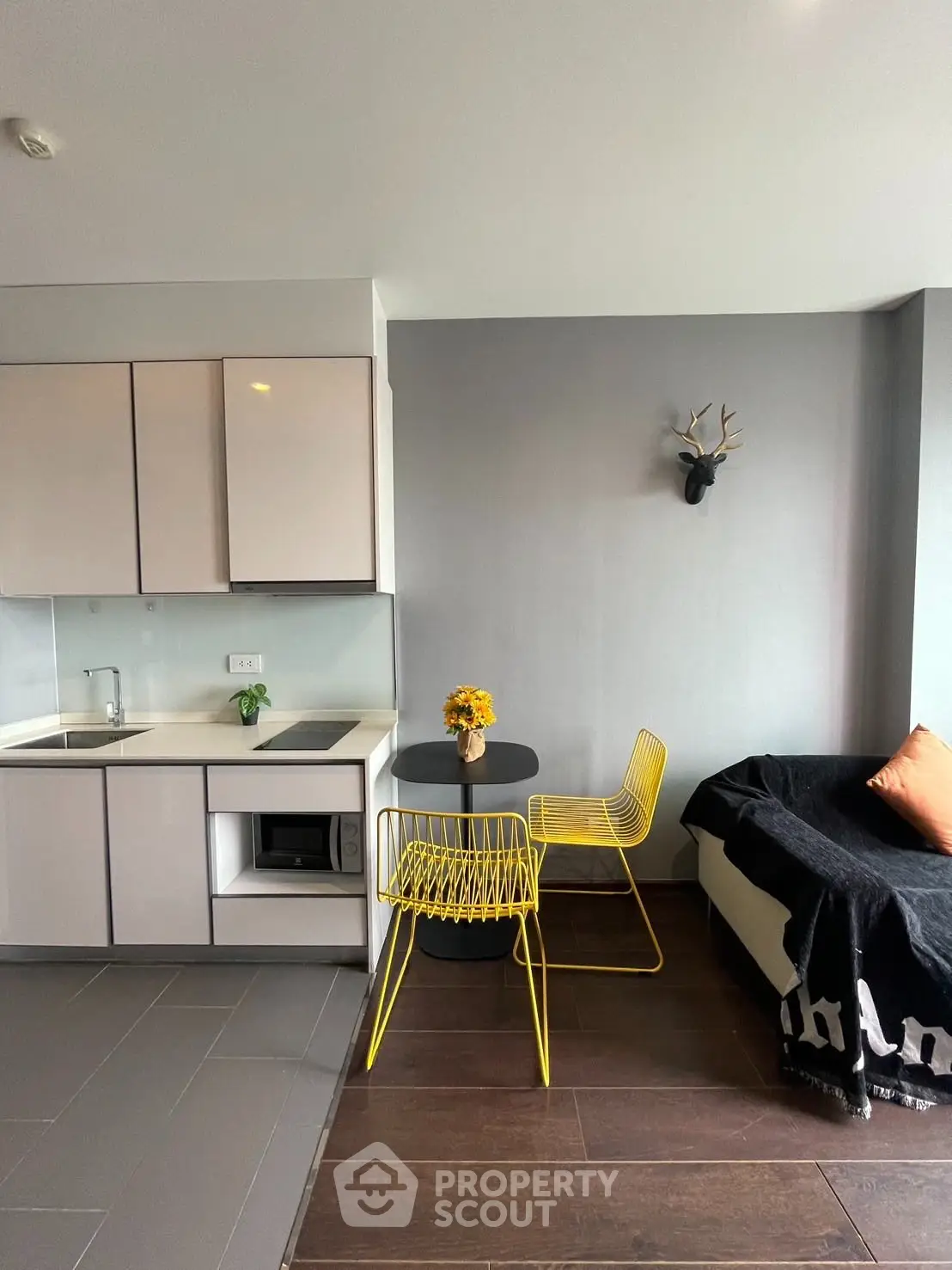 Modern living room with sleek kitchen and stylish decor, featuring yellow chairs and a cozy sofa.