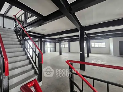 Spacious industrial-style open floor plan with modern staircase and large windows.