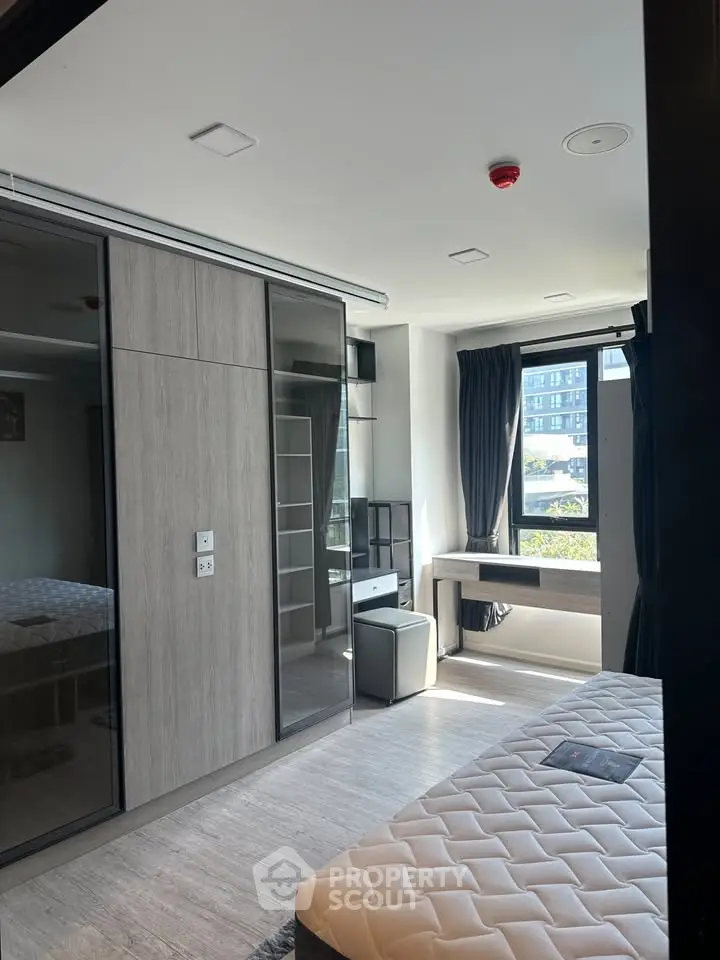 Modern bedroom with large window and built-in wardrobe in a stylish apartment.
