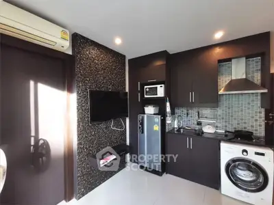 Modern kitchen with sleek cabinets, washing machine, and stainless steel appliances.