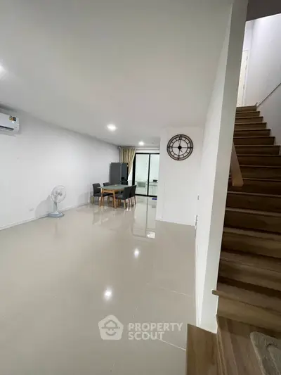 Spacious modern living room with sleek staircase and dining area