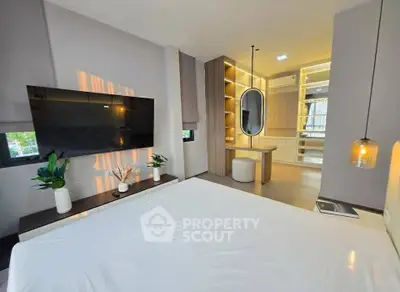 Modern bedroom with stylish decor, large TV, and elegant lighting, showcasing a luxurious and inviting atmosphere.