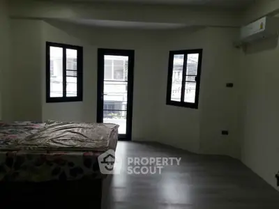 Spacious bedroom with modern flooring and large windows for natural light.