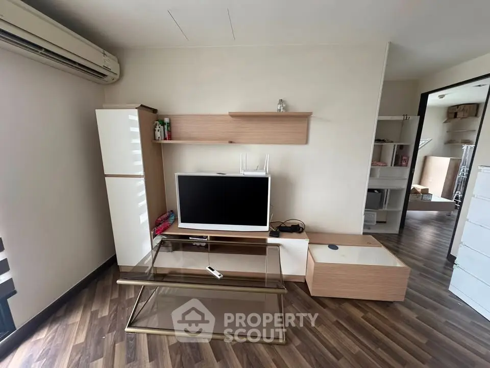 Modern living room with sleek furniture and wooden flooring, featuring a TV and stylish shelving.