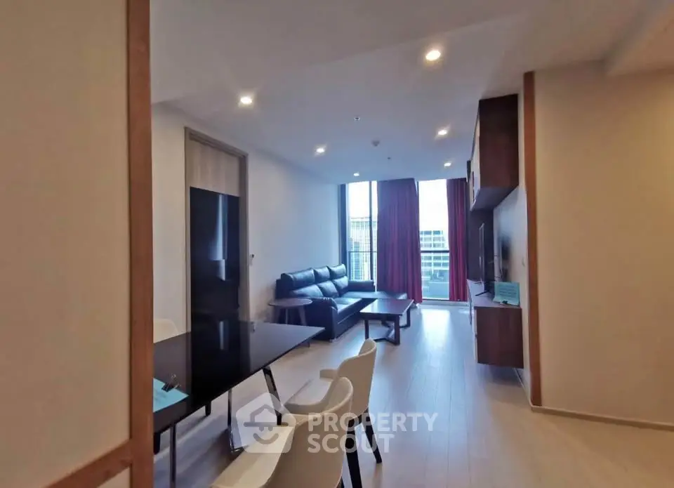 Modern living room with sleek furniture and large window offering city view.