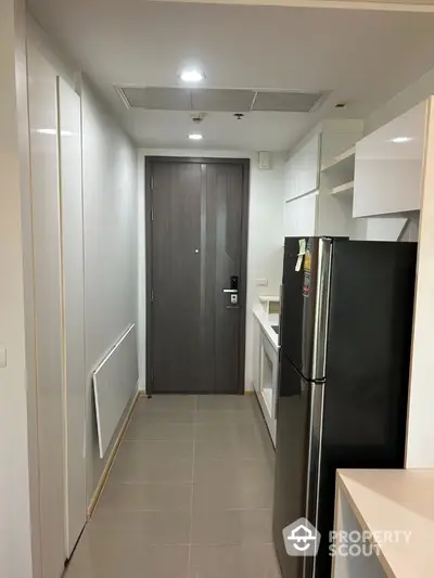 Modern apartment entrance with sleek kitchen and stainless steel fridge