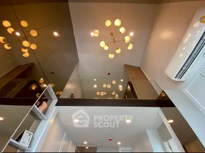 Modern loft interior with stylish lighting and glass railing, showcasing contemporary design and high ceilings.