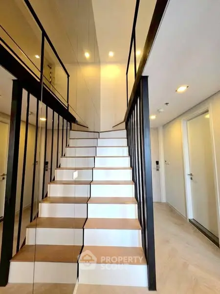 Modern staircase with sleek design and mirrored walls in a stylish home interior.