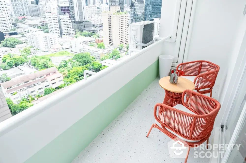 Stunning city view from modern high-rise balcony with stylish seating area.