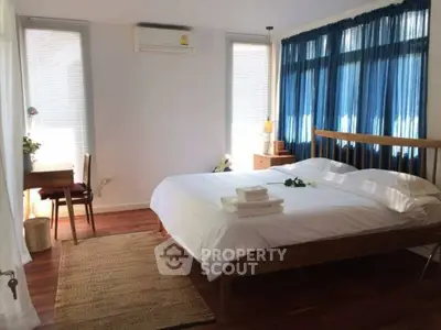 Charming bedroom with natural light, wooden flooring, and cozy decor for a serene living experience.