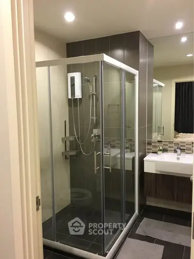 Modern bathroom with glass shower enclosure and sleek vanity in contemporary apartment.
