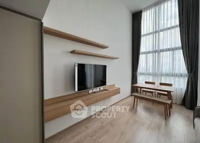 Modern living room with high ceilings, wooden flooring, and stylish furniture in a bright apartment.