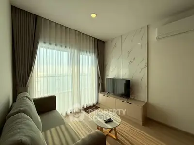 Modern living room with natural light, stylish sofa, and TV setup.