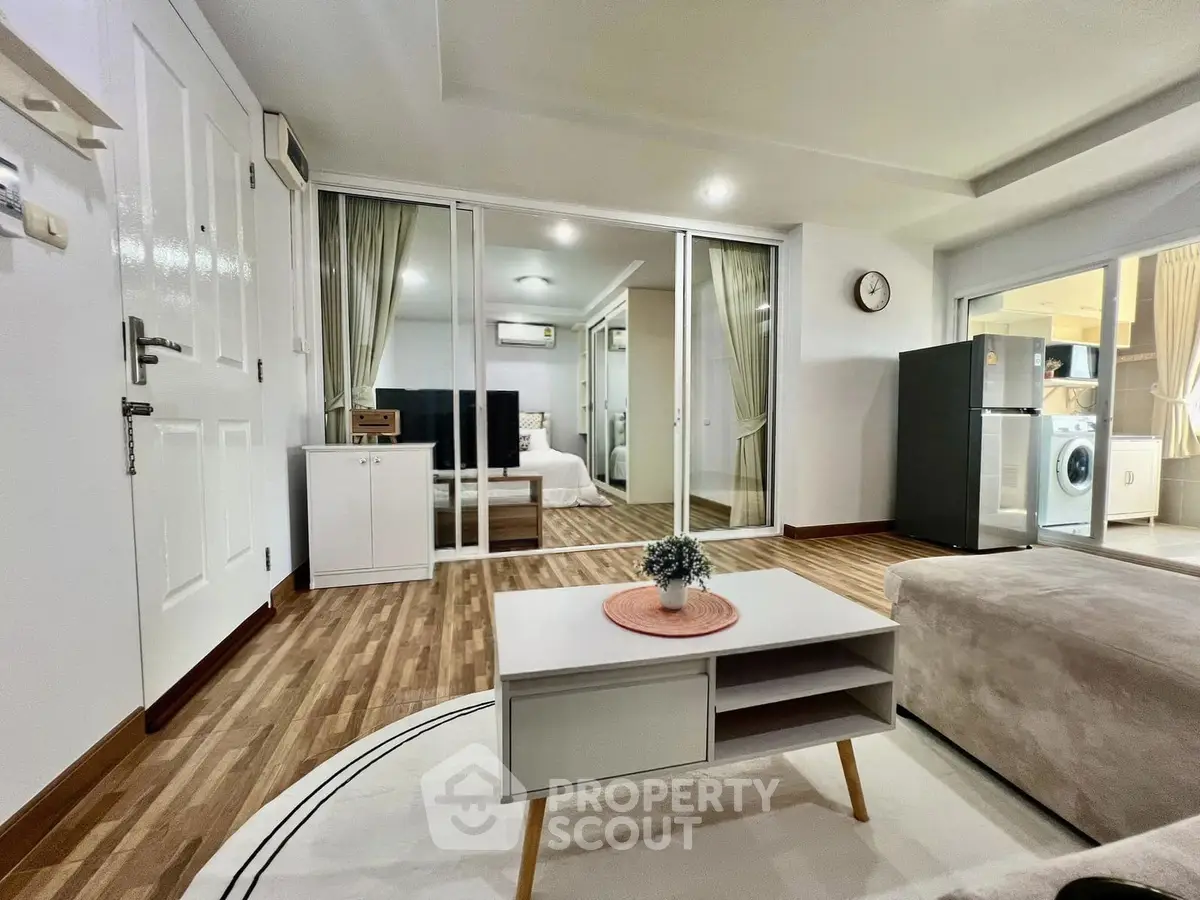 Modern living room with sleek design, featuring hardwood floors, a cozy sofa, and a view into a stylish bedroom.
