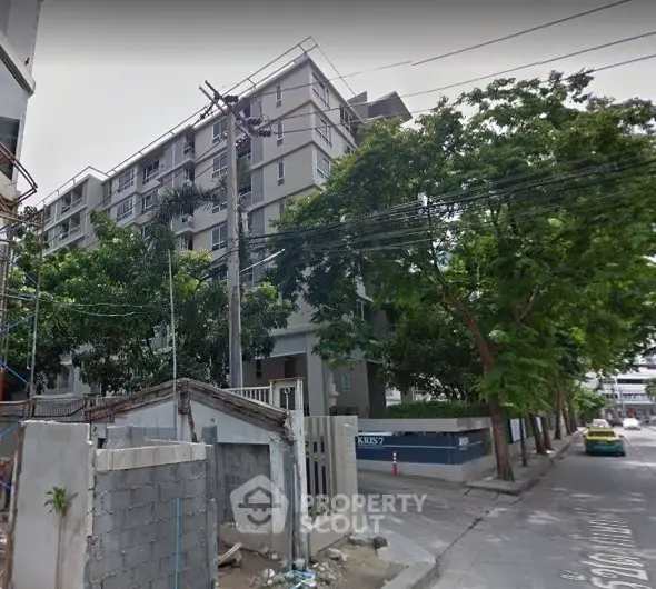 Modern mid-rise apartment building with lush greenery and street view.
