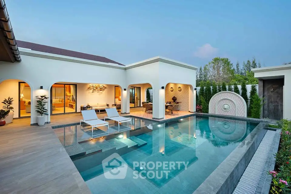 Luxurious villa with private pool and elegant outdoor seating area at sunset.