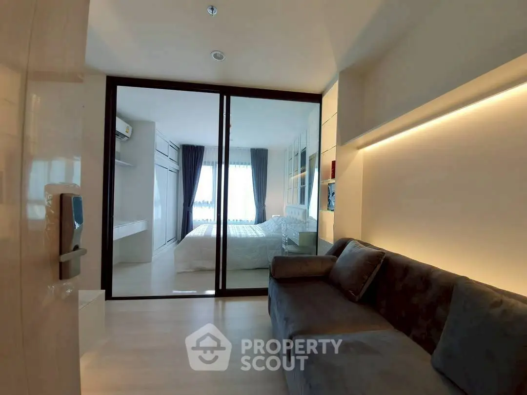 Modern living room with glass partition leading to a stylish bedroom