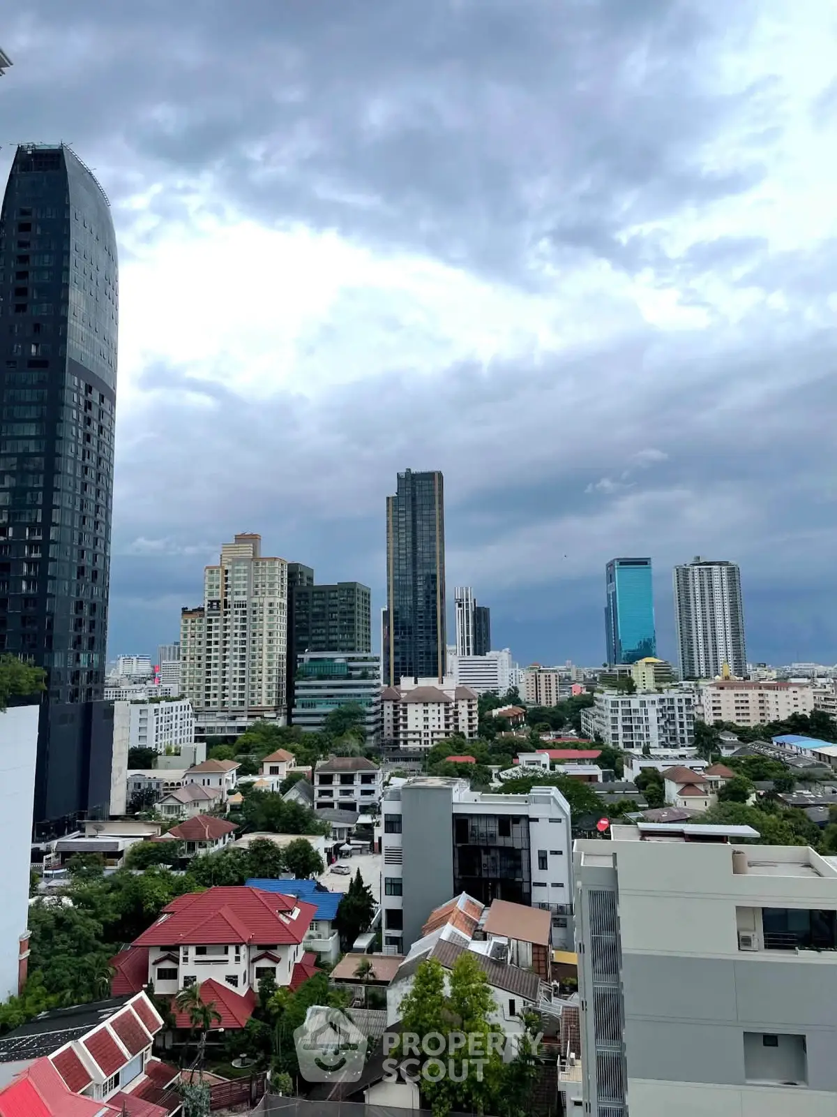 Stunning cityscape view with modern skyscrapers and residential buildings under a dramatic cloudy sky.