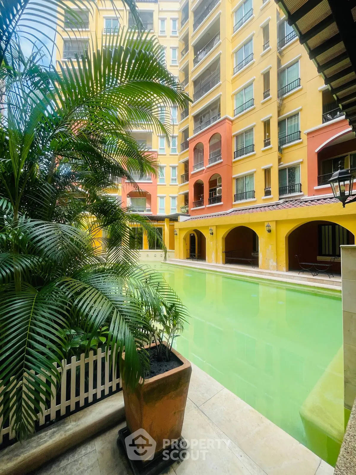 Charming apartment building with vibrant colors and inviting pool area.