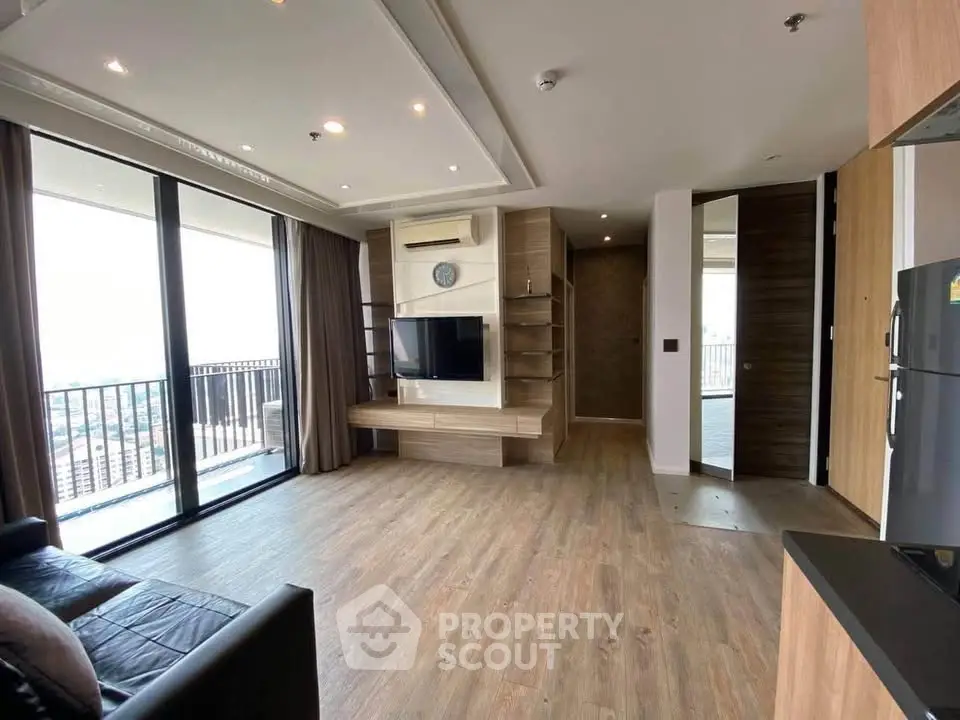 Spacious modern living room with balcony and city view, featuring sleek wooden flooring and contemporary design.