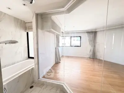 Spacious modern bathroom with glass partition and wooden flooring