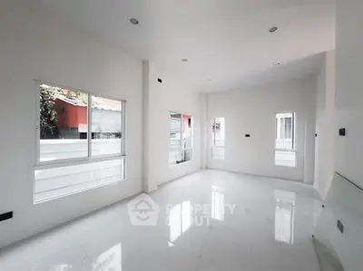 Spacious modern living room with large windows and sleek white tiles.