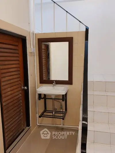 Compact and functional bathroom with wall-mounted sink, large mirror, and neutral tile design, ideal for modern urban living.