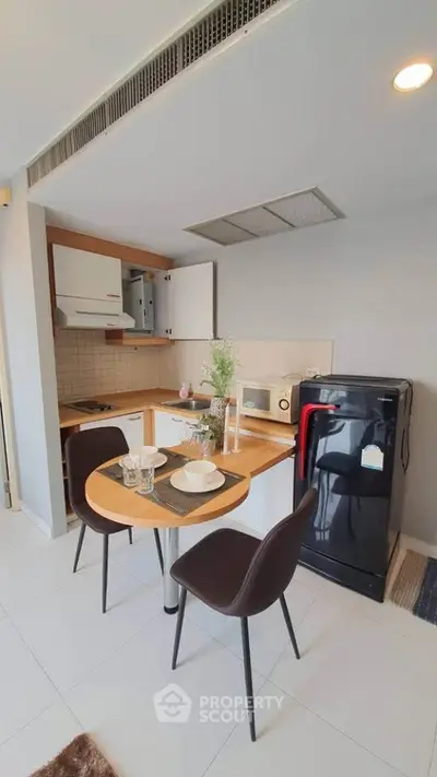 Modern kitchen with compact dining area and sleek appliances in a cozy apartment setting.