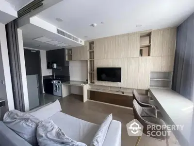 Modern living room with built-in storage and compact kitchen featuring washing machine.