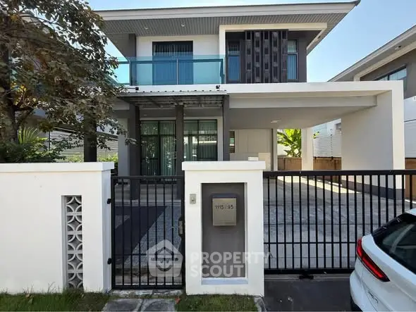 Modern two-story house with gated entrance and driveway in a suburban neighborhood.