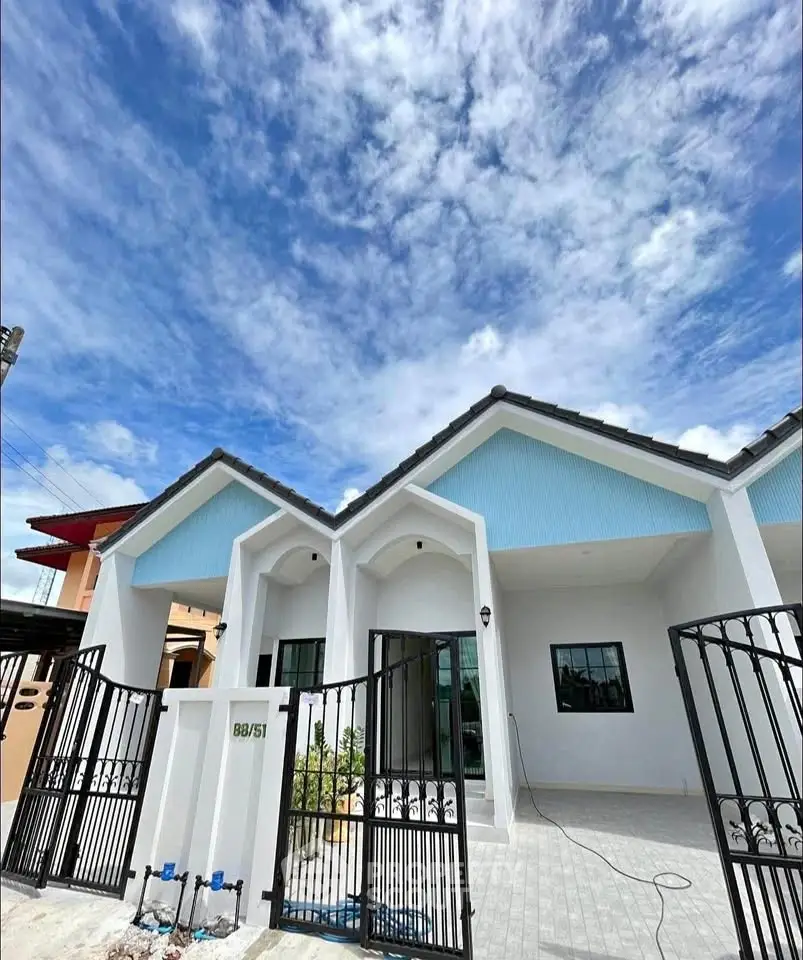Charming single-story home with modern facade and gated entrance under a vibrant blue sky.
