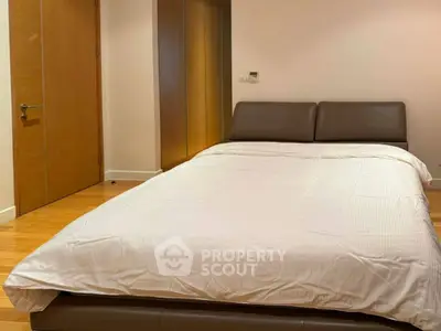 Spacious bedroom with modern design and wooden flooring, featuring a comfortable double bed and ample closet space.