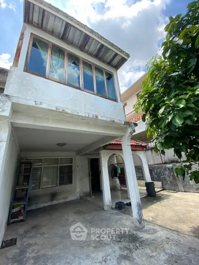 Charming two-story fixer-upper with potential, featuring a spacious outdoor area and rustic architectural elements.